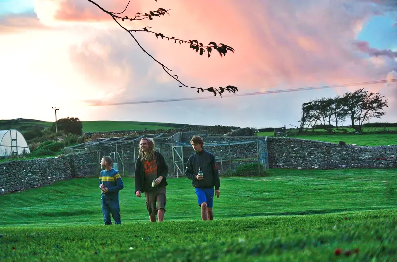 People crossing a field at Cowran Estate beneath a vivid evening sky